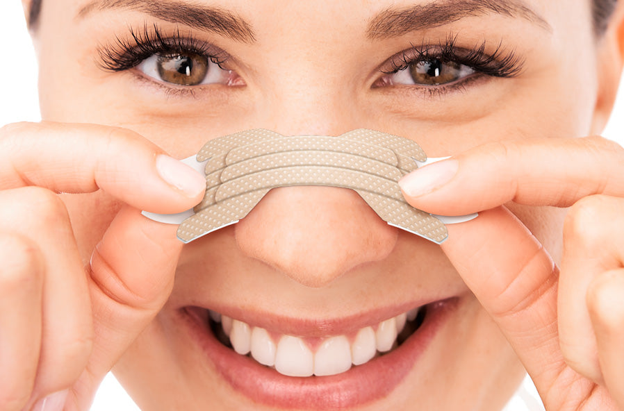 woman properly placing a clear passage nasal strip on the center of her nose